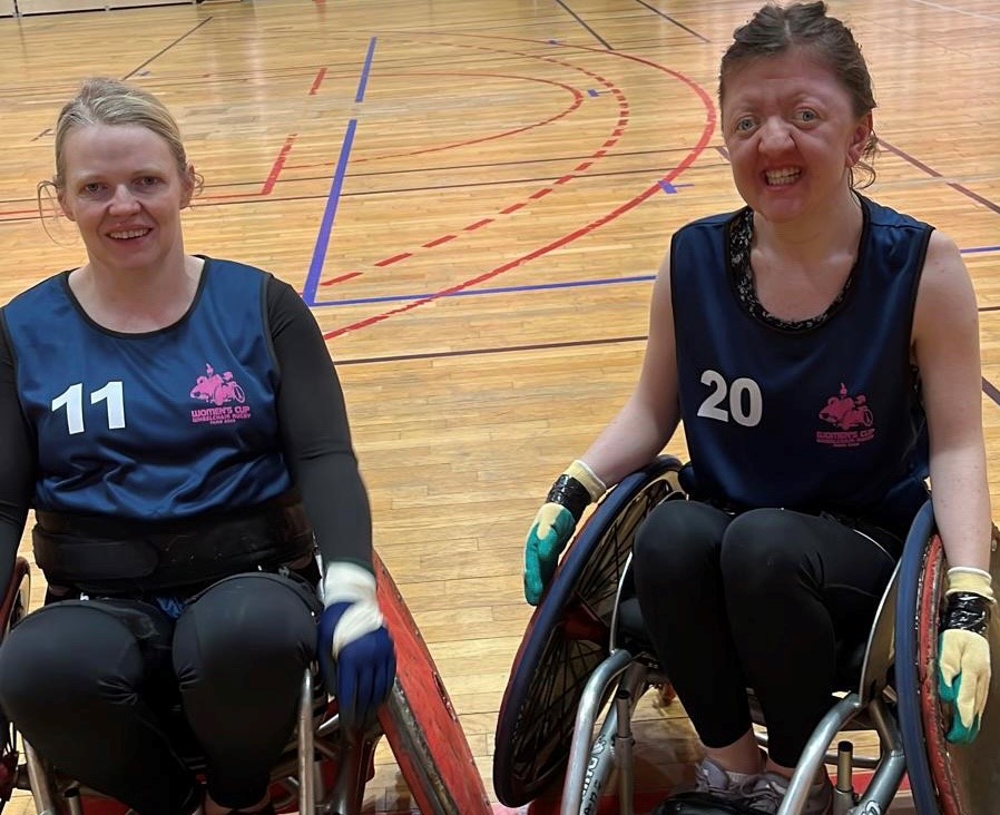 Deirdre Mongan (left) and Jade Flynn-Hurley (right) pose for a picture in their Women's Cup jerseys while sitting in their rugby wheelchairs.
